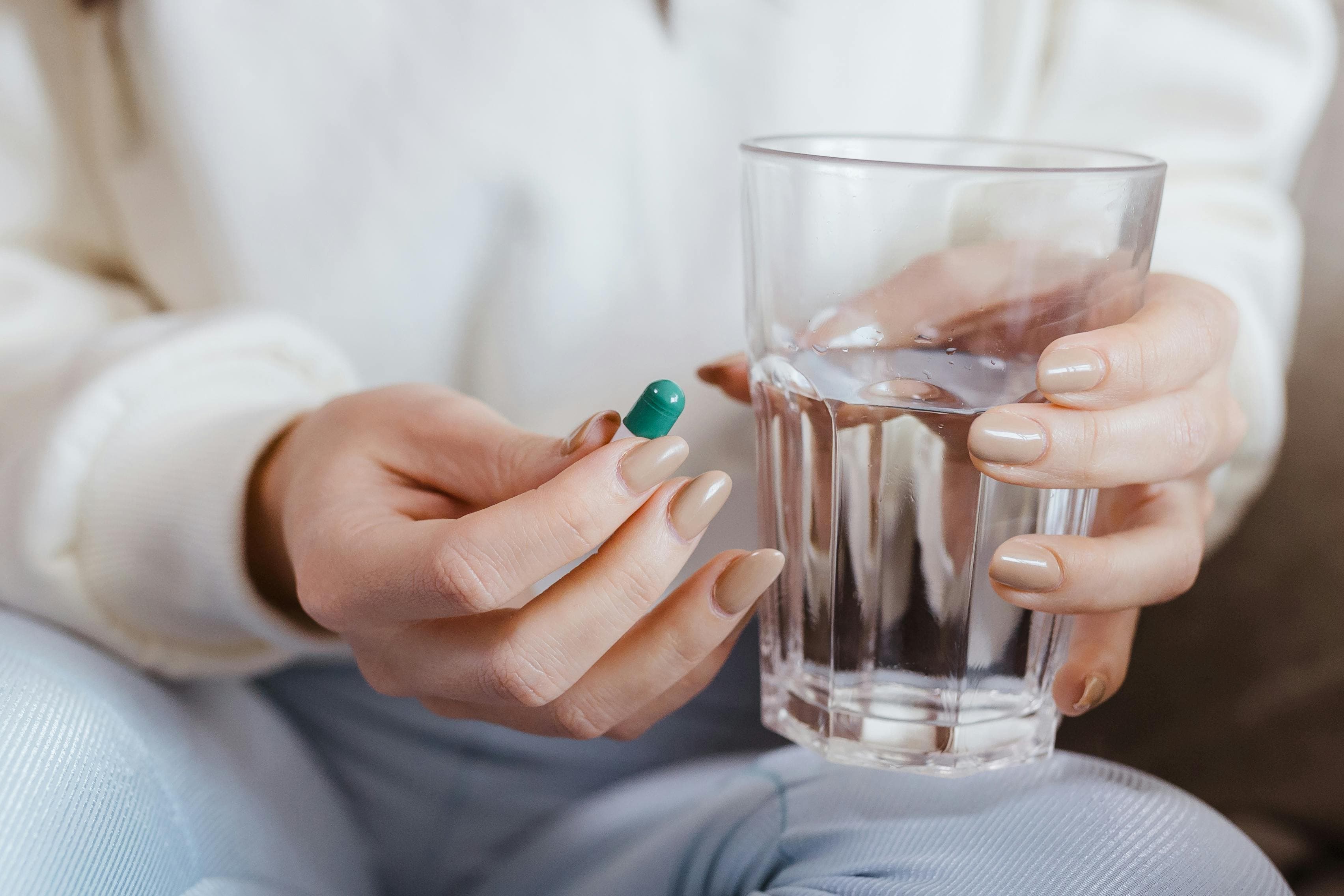 A woman taking a magnesium supplement with a glass of water
