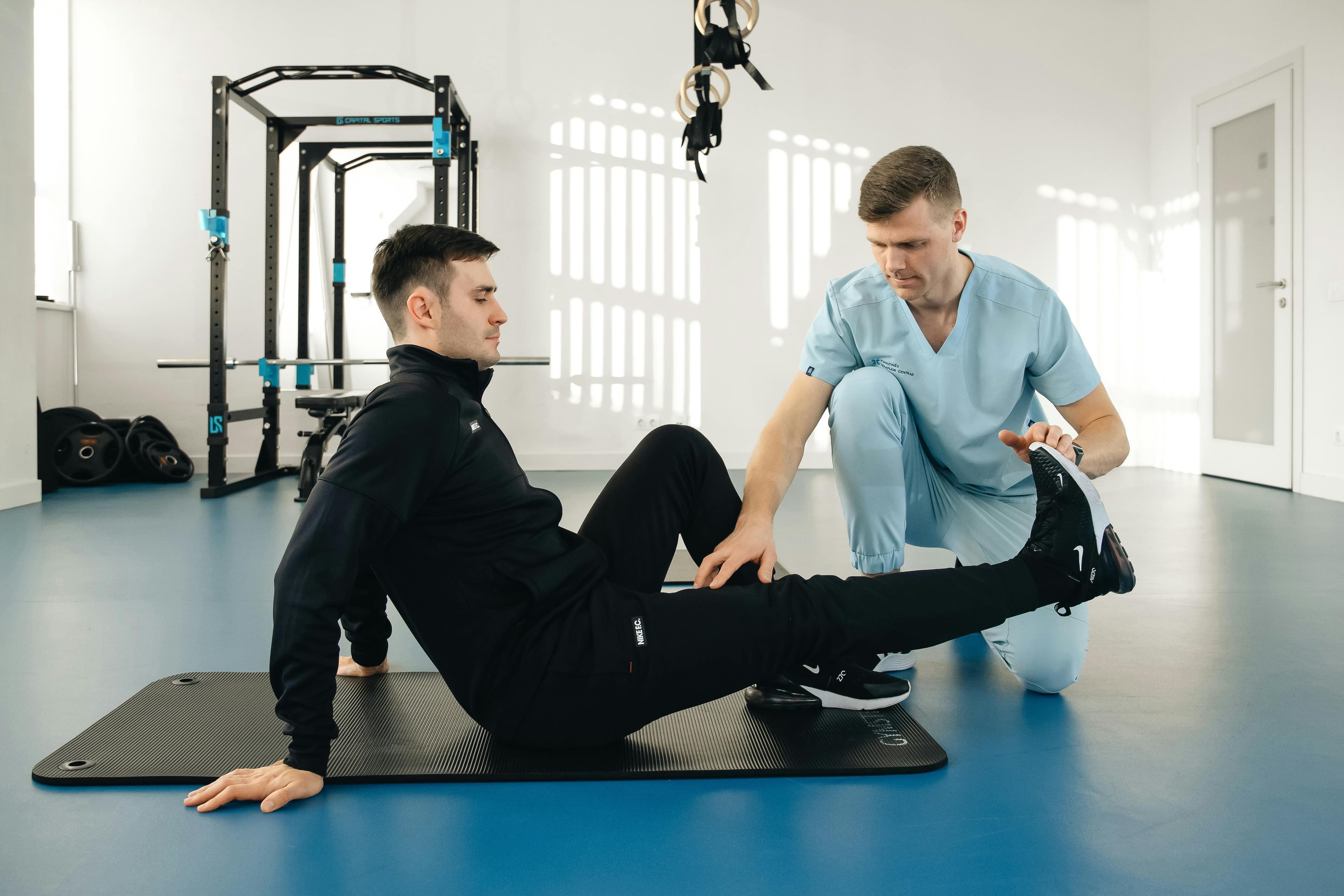 A physical therapist working with a patient on gait training using parallel bars in a rehabilitation setting