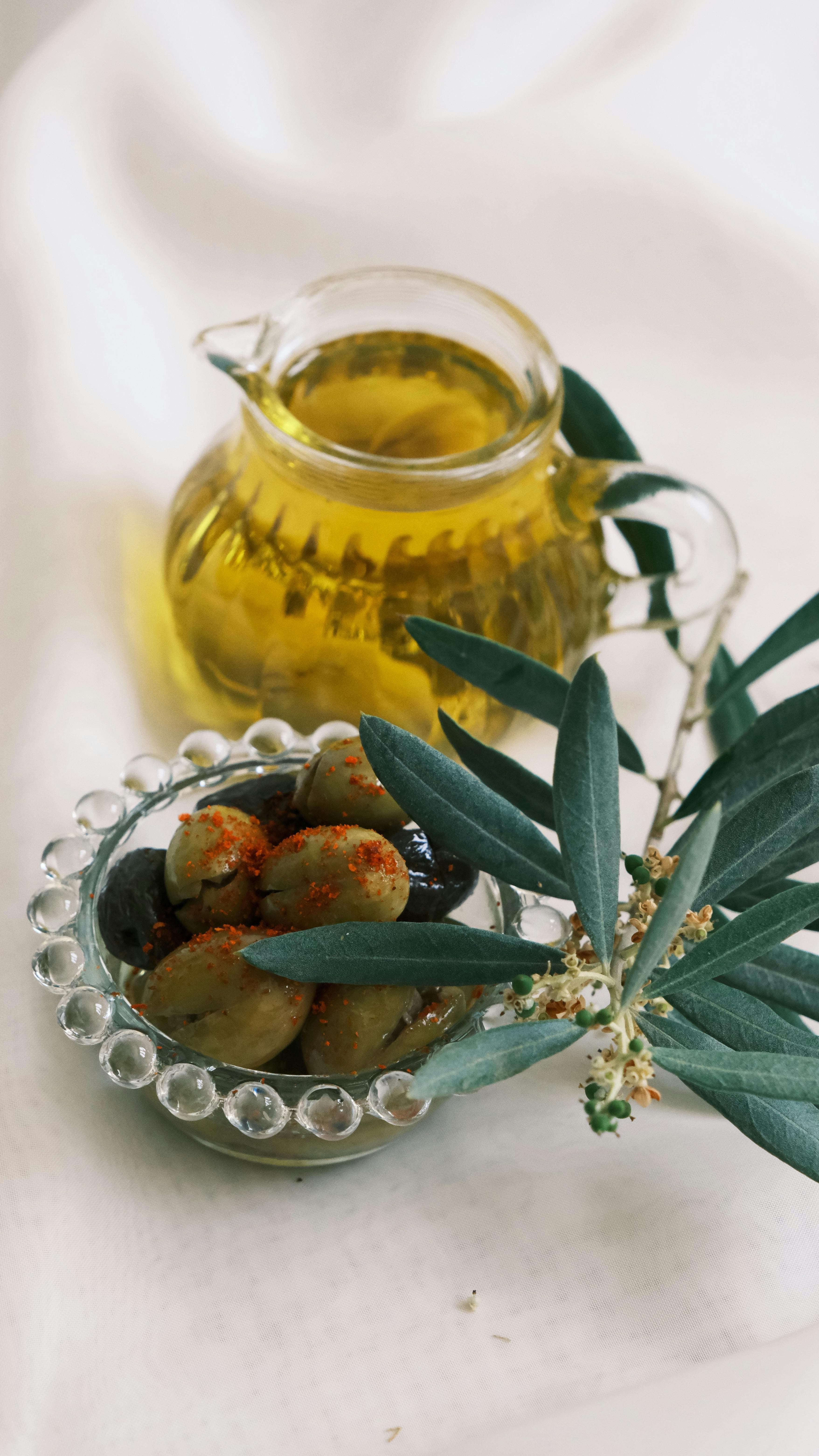 A bottle of extra virgin olive oil next to fresh olives