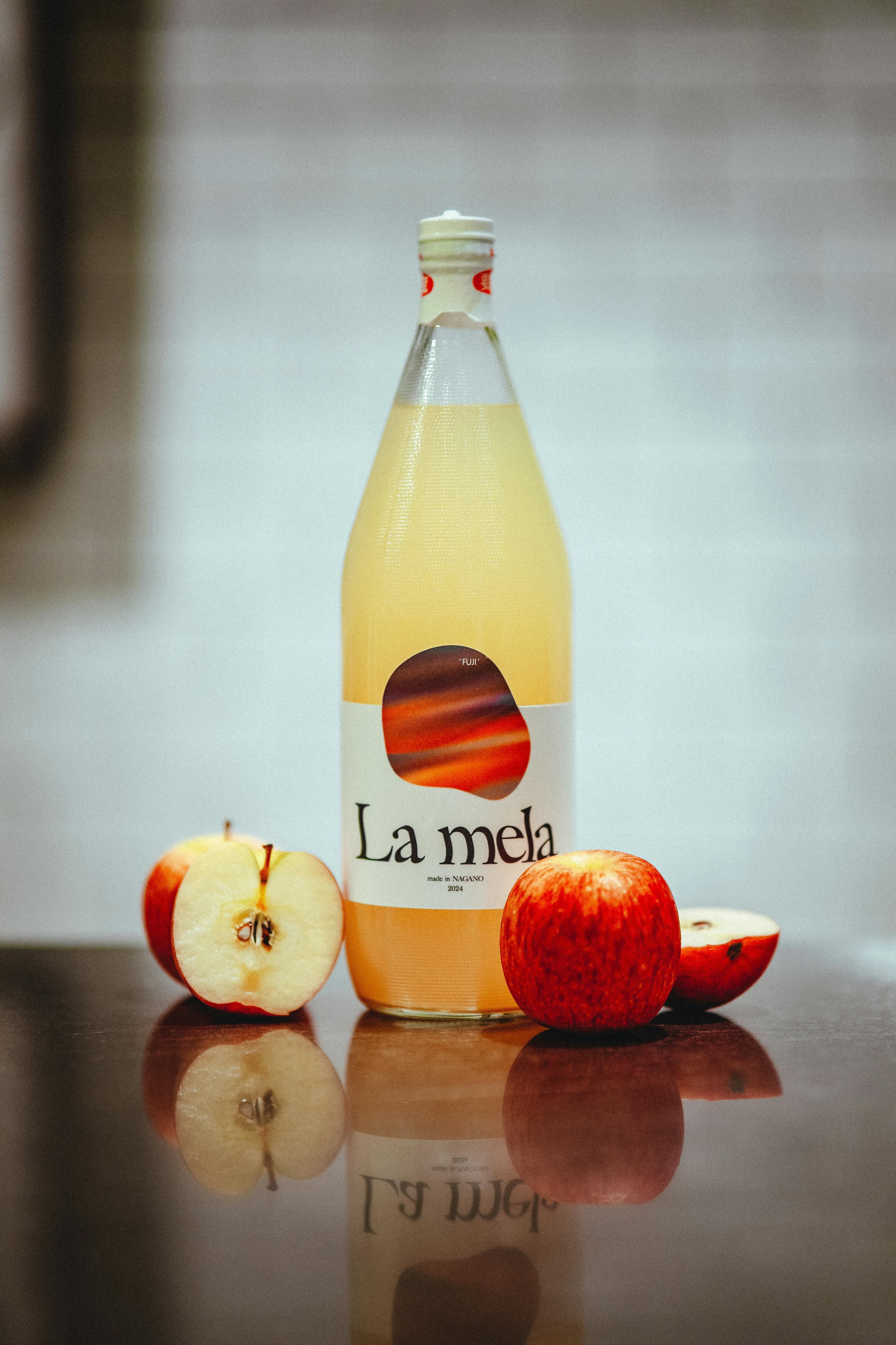 A bottle of apple cider vinegar next to fresh apples