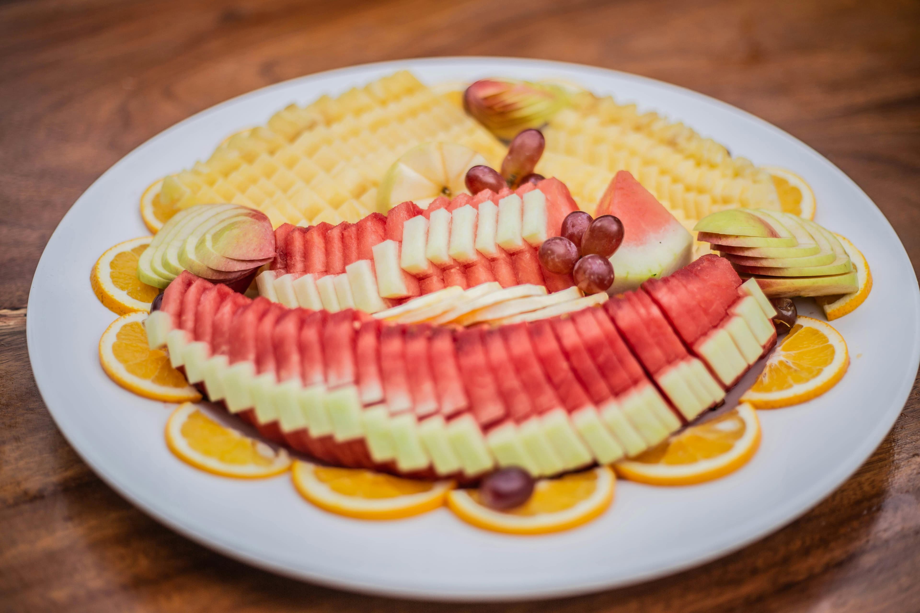 A colorful platter with various kidney-friendly fruits including cranberries, blueberries, grapes, apples, and pineapple