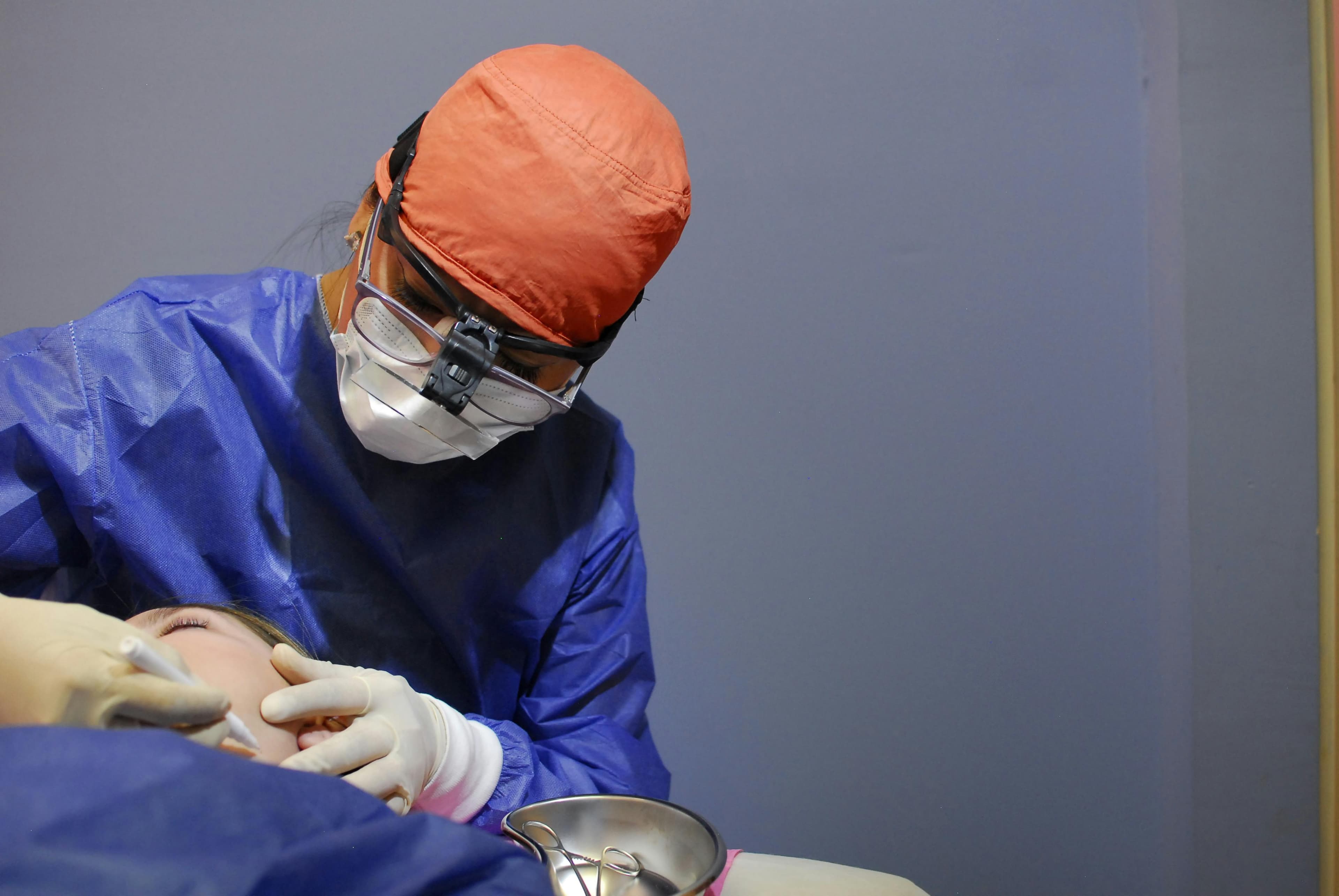 Doctor examining a patient's lip with a blue lesion