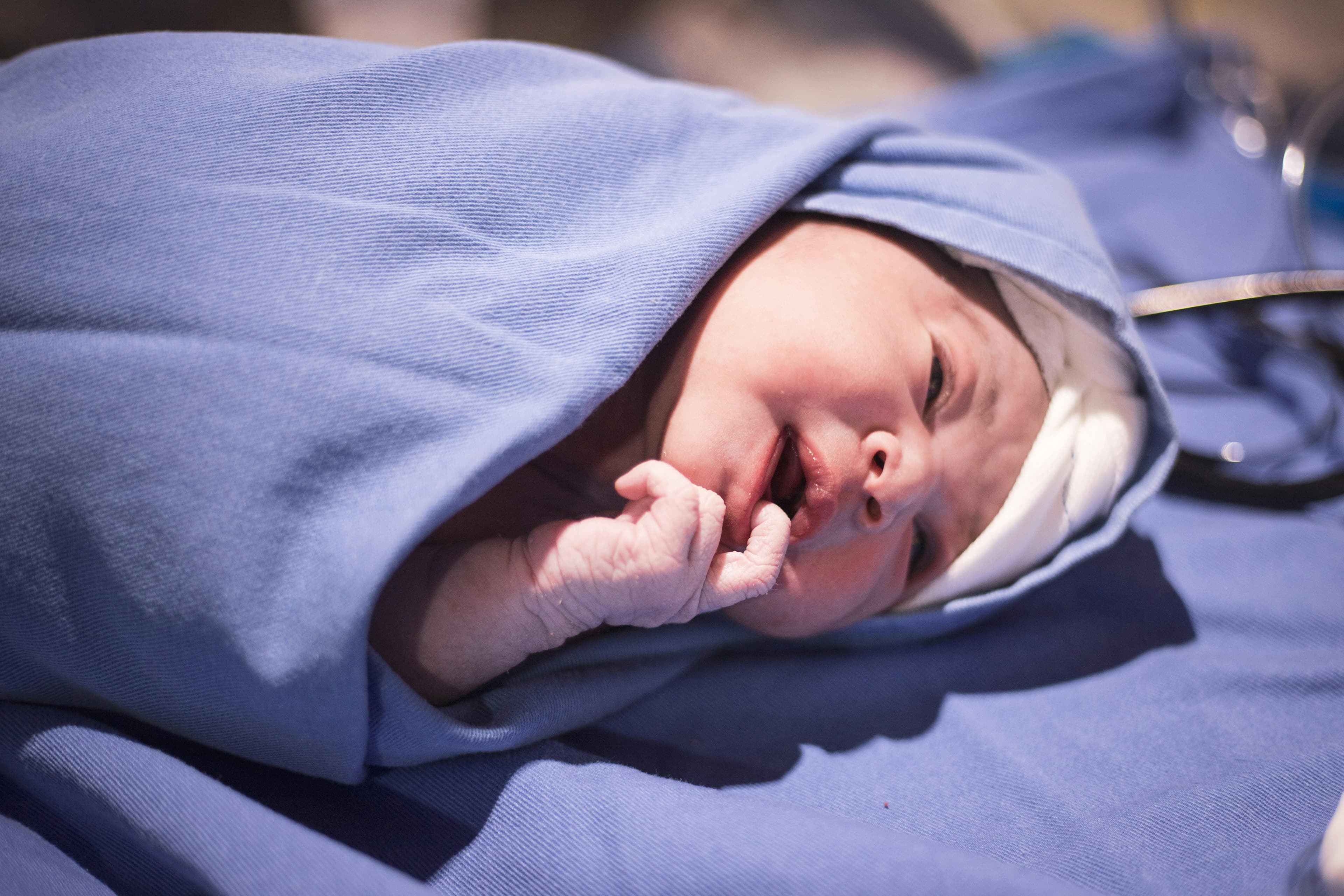 A baby gently rubbing their eyes with their hands