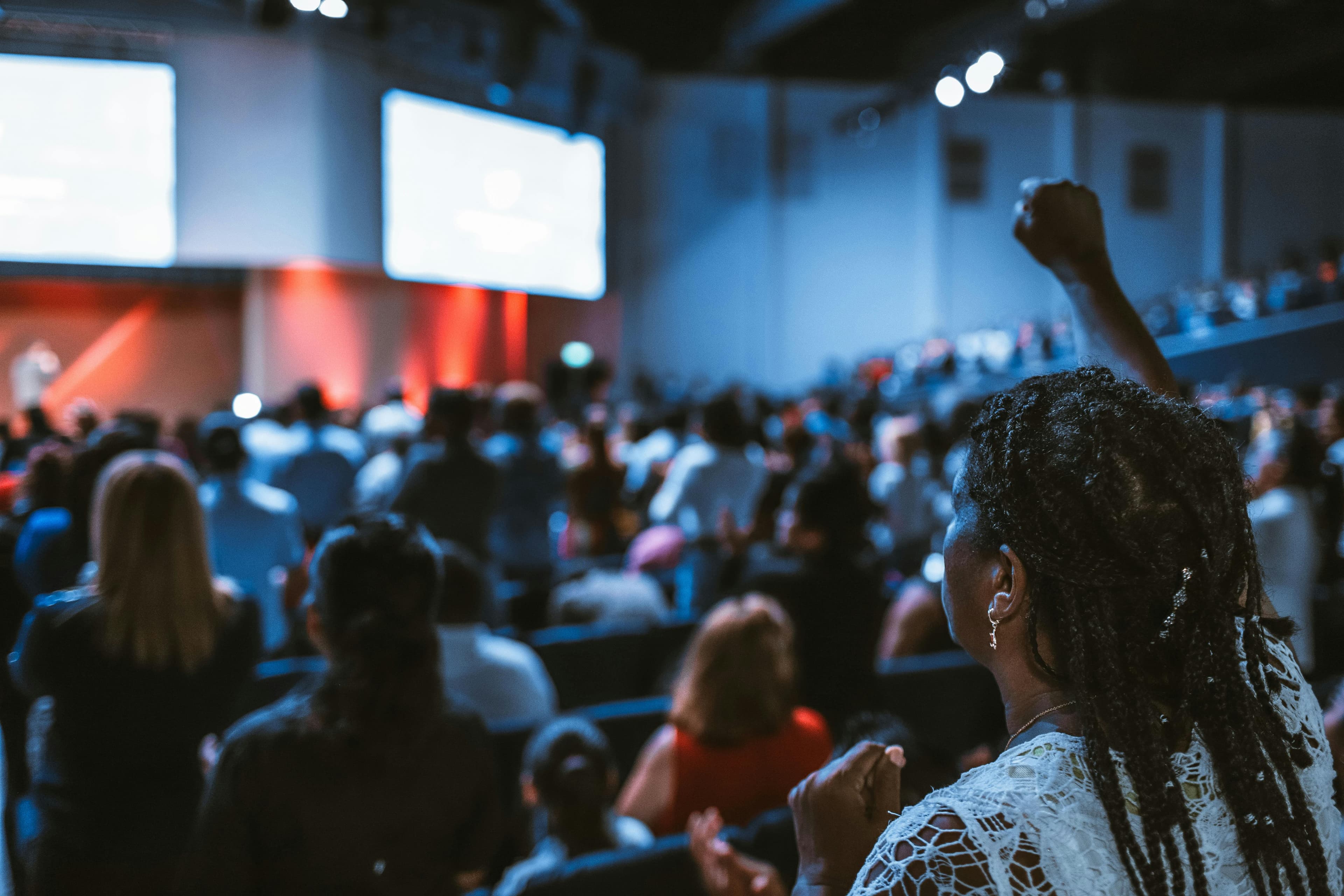 A large conference hall filled with attendees listening to a keynote speaker on stage