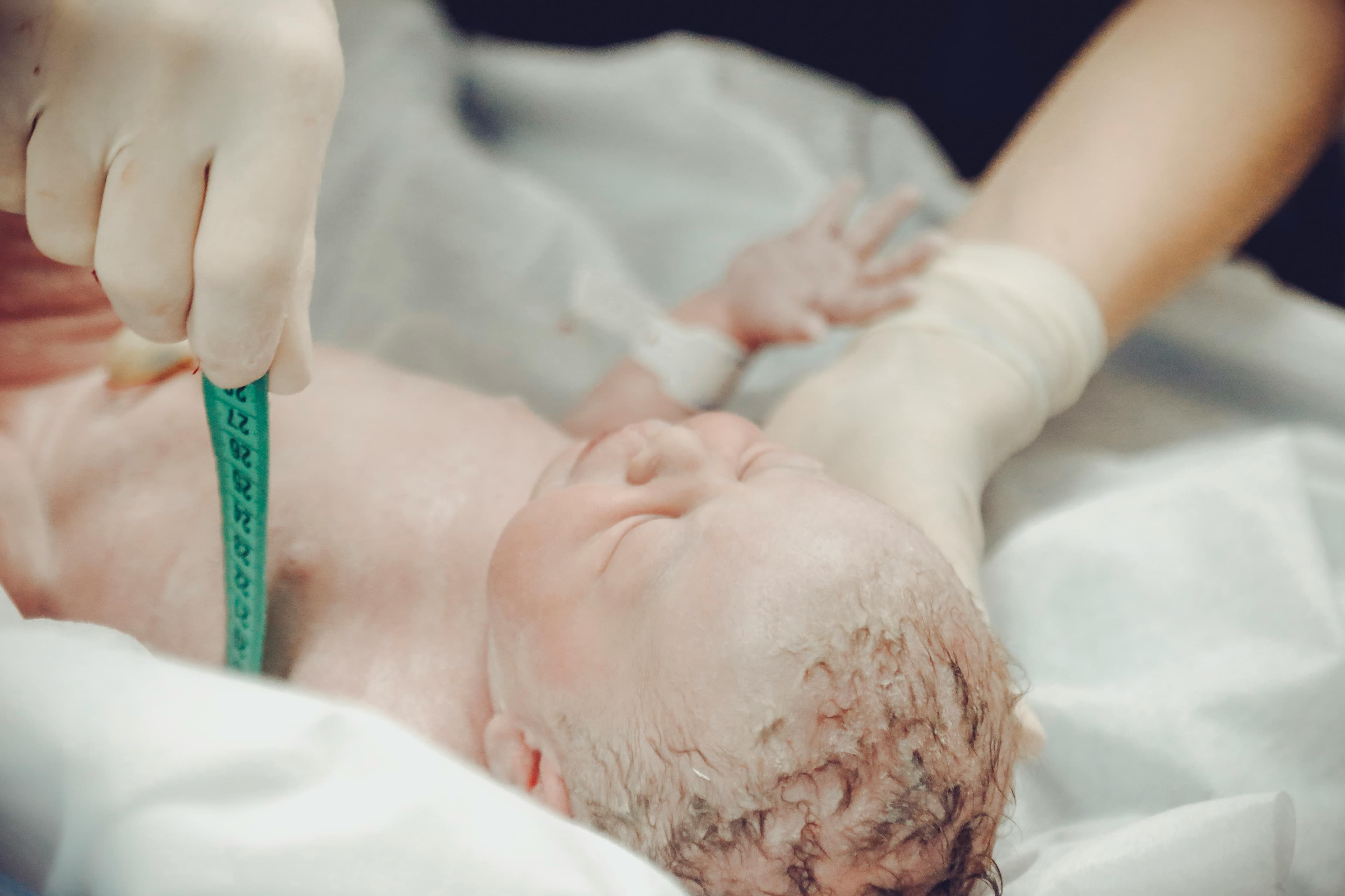 A medical professional performing delayed cord clamping on a newborn baby