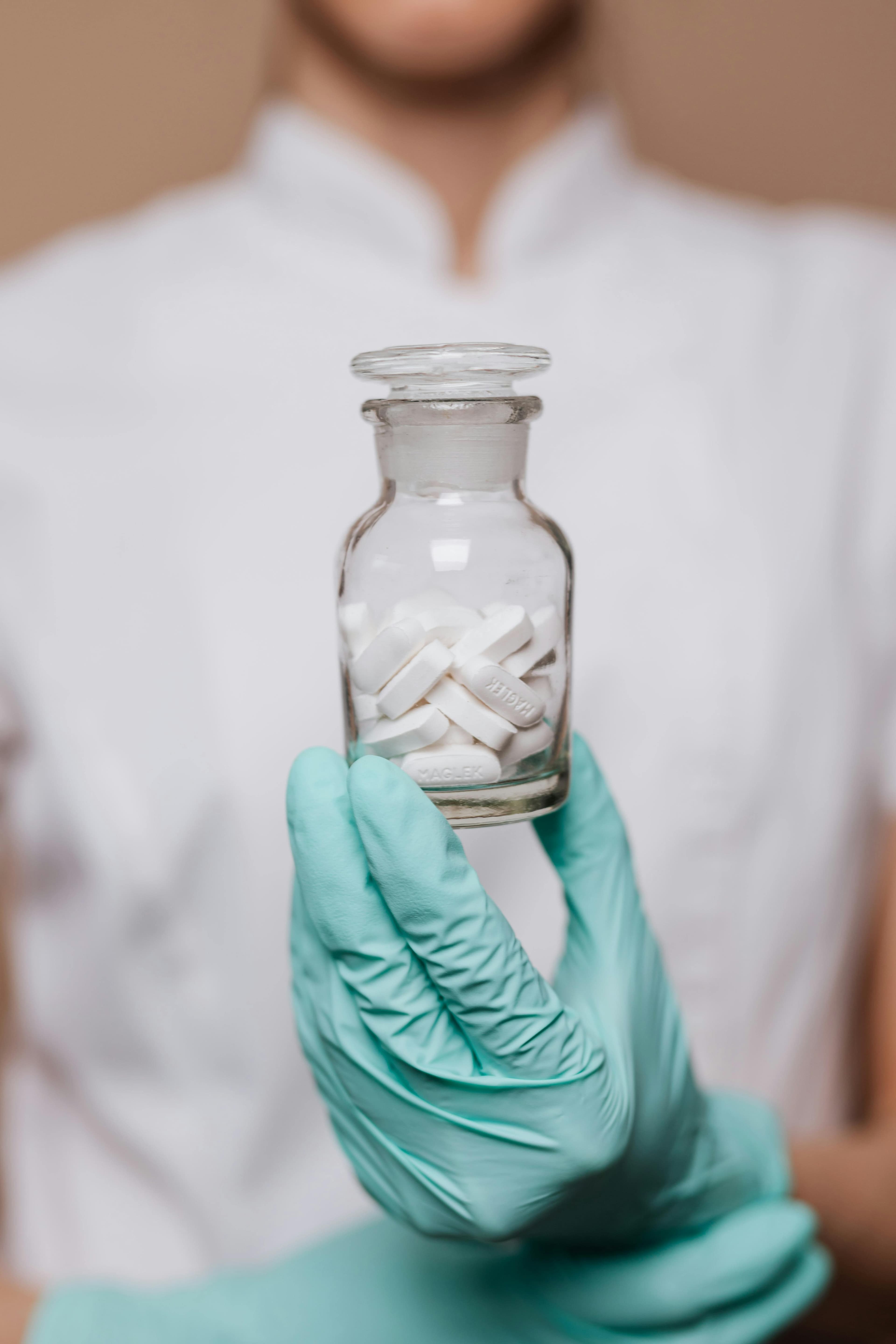 A medical professional reviewing multiple medication bottles, representing polypharmacy in ICU settings