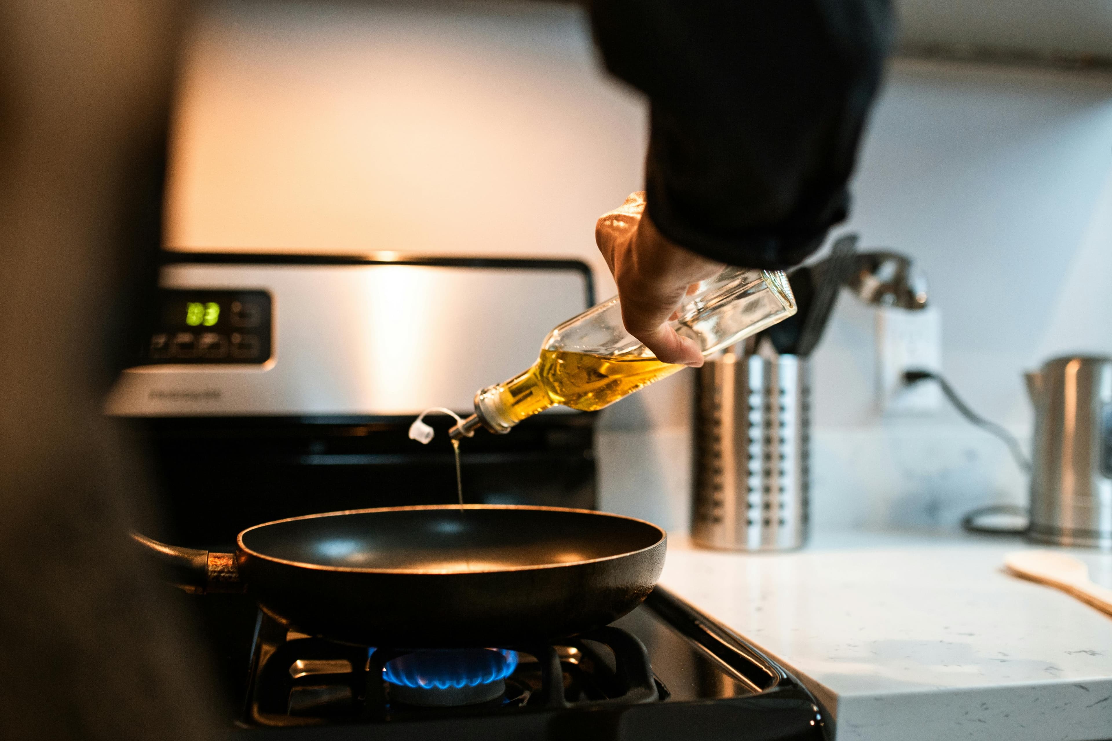 A bottle of extra virgin olive oil with fresh olives