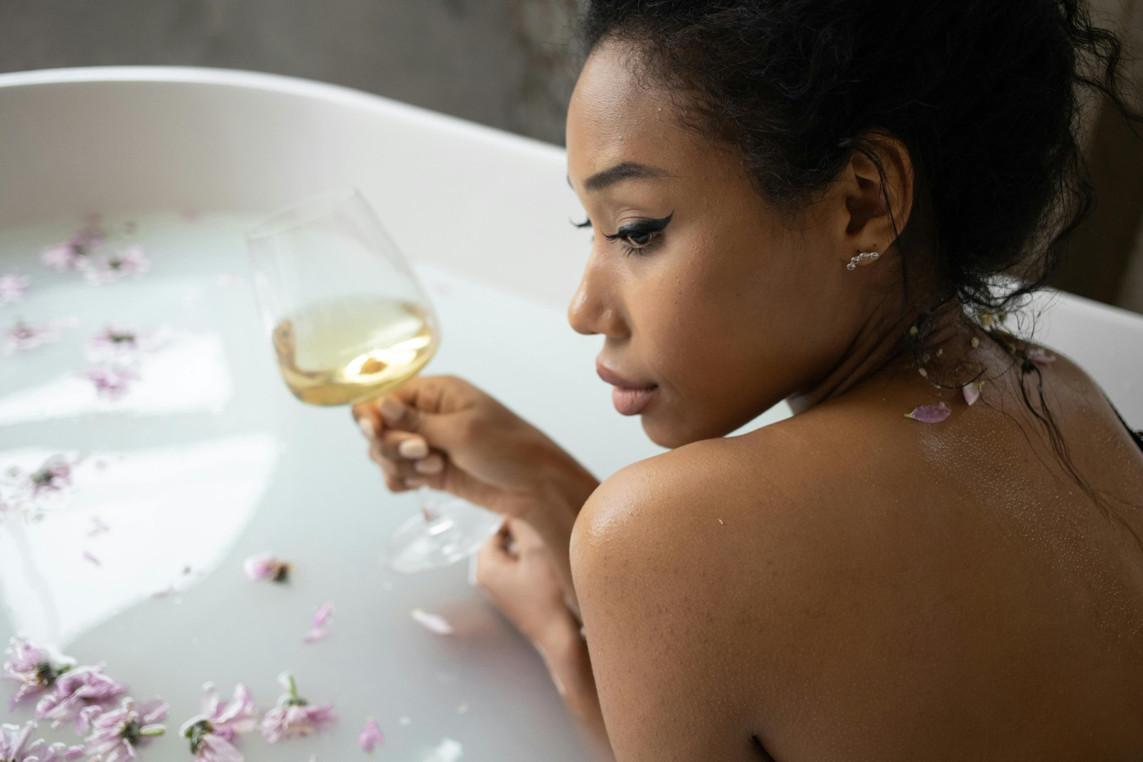 Woman drinking water from a glass while looking at her phone
