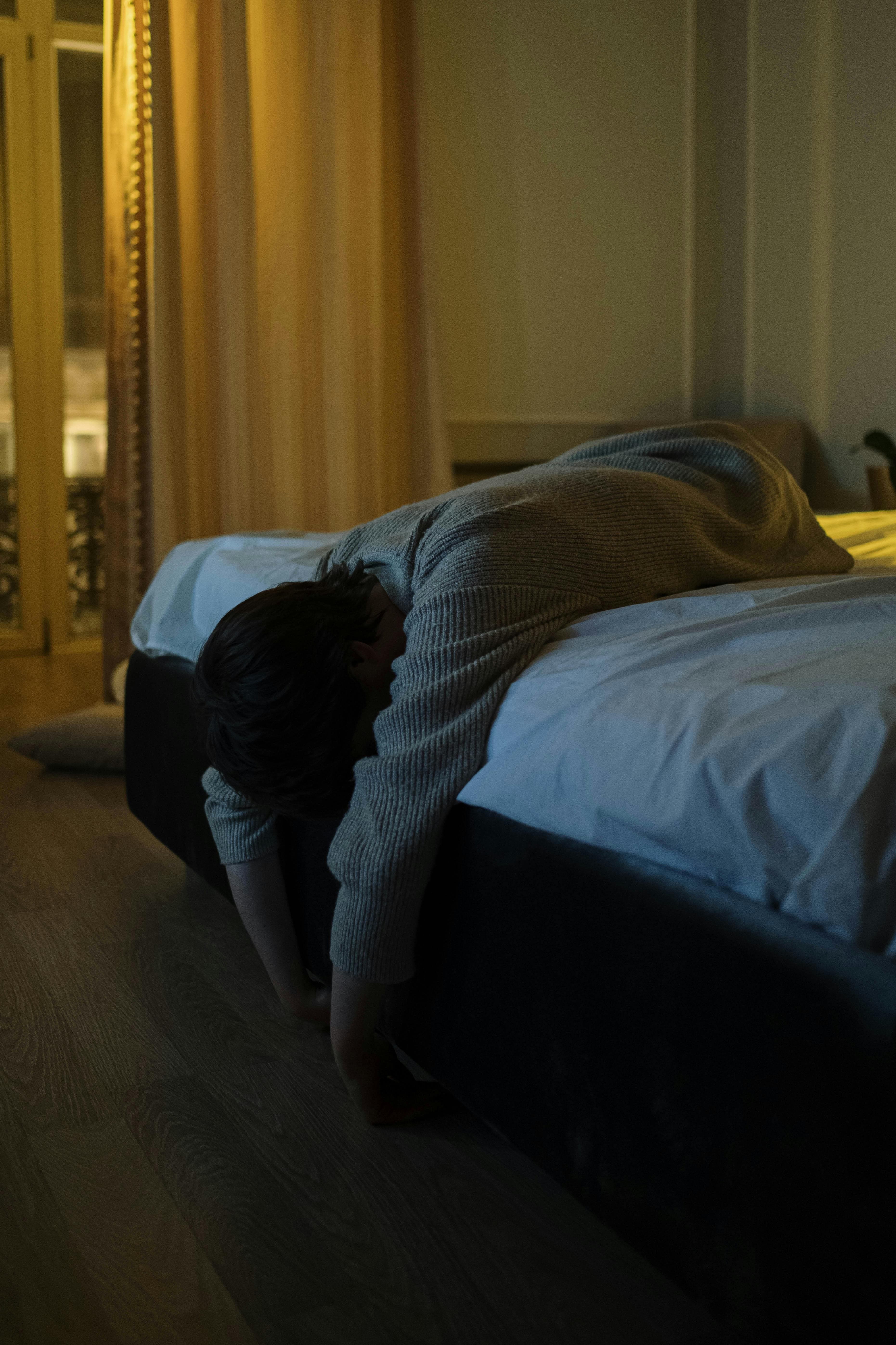 Person scratching their feet while lying in bed, illustrating the discomfort of nocturnal itching