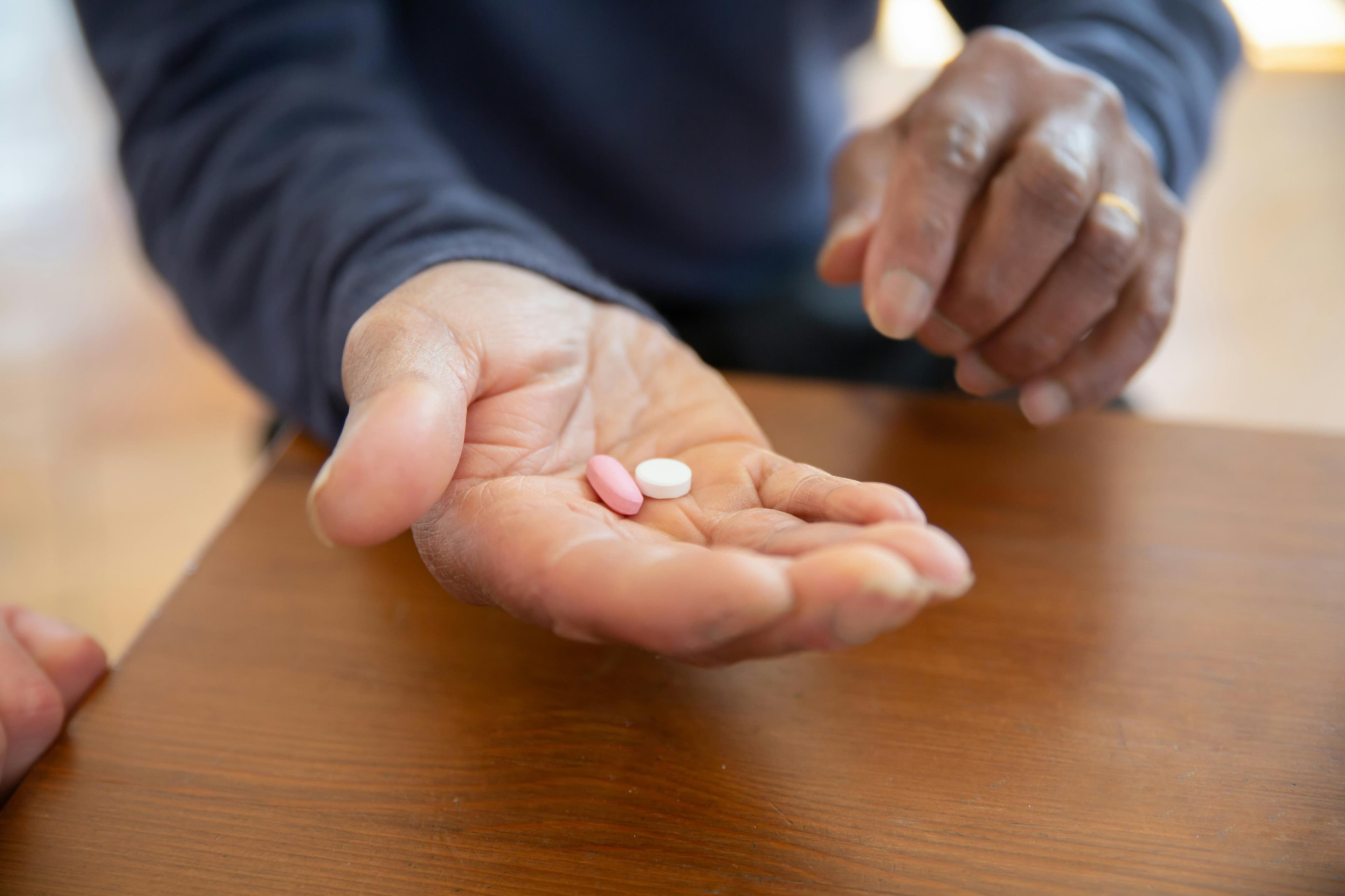 An elderly person's hand holding various prescription medications