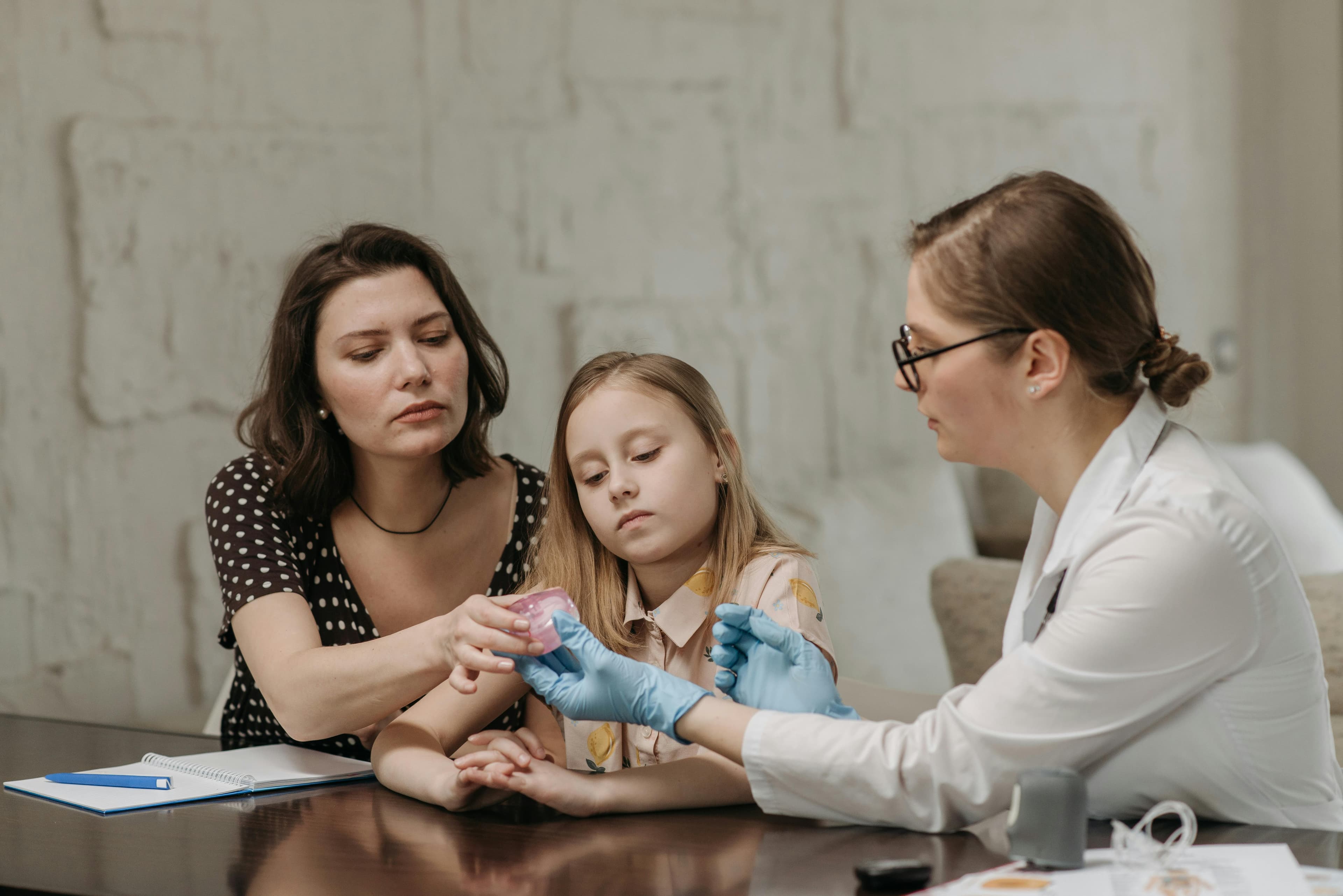 A doctor consulting with a young patient and parent in a medical office