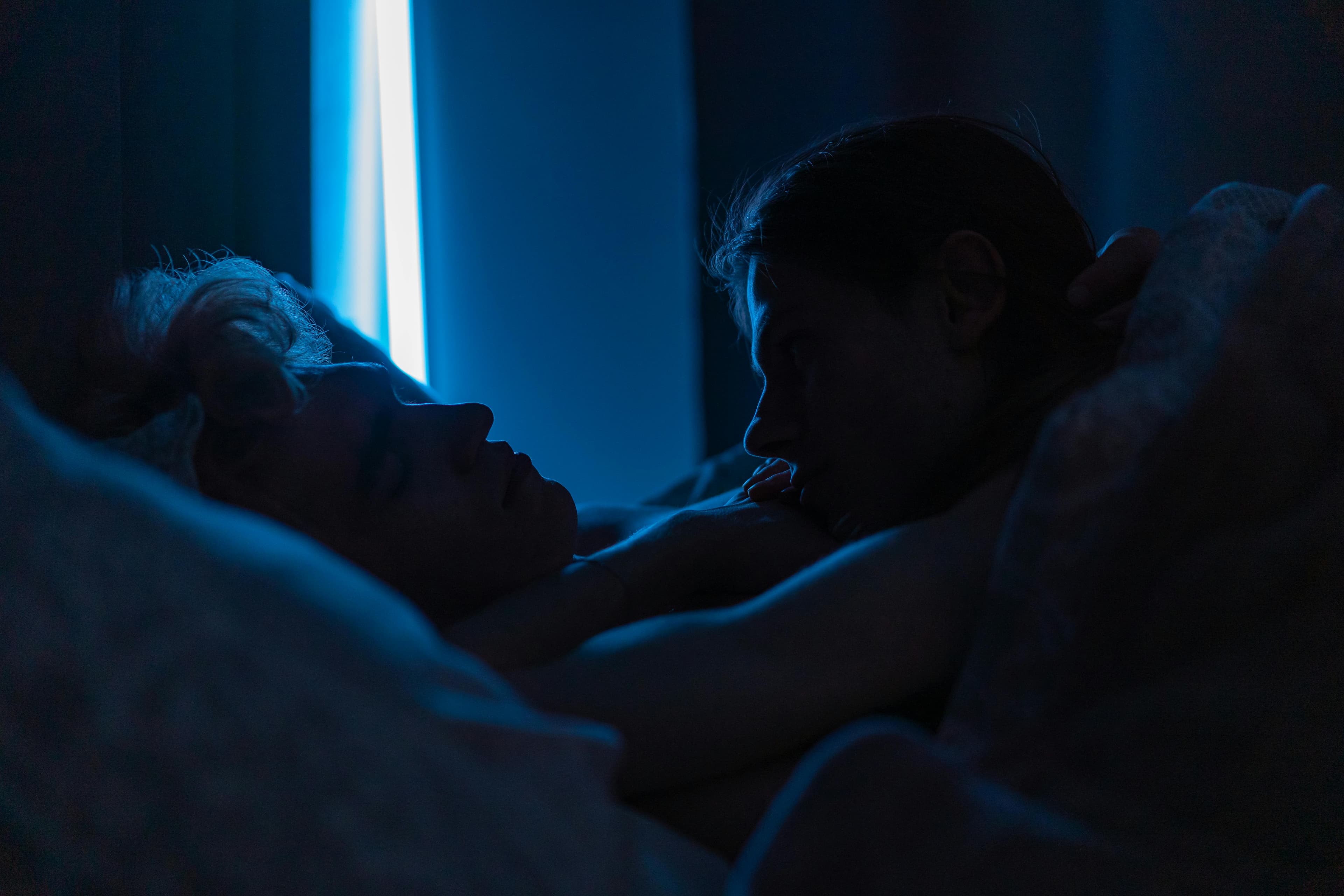 A couple lying awake in bed, looking frustrated
