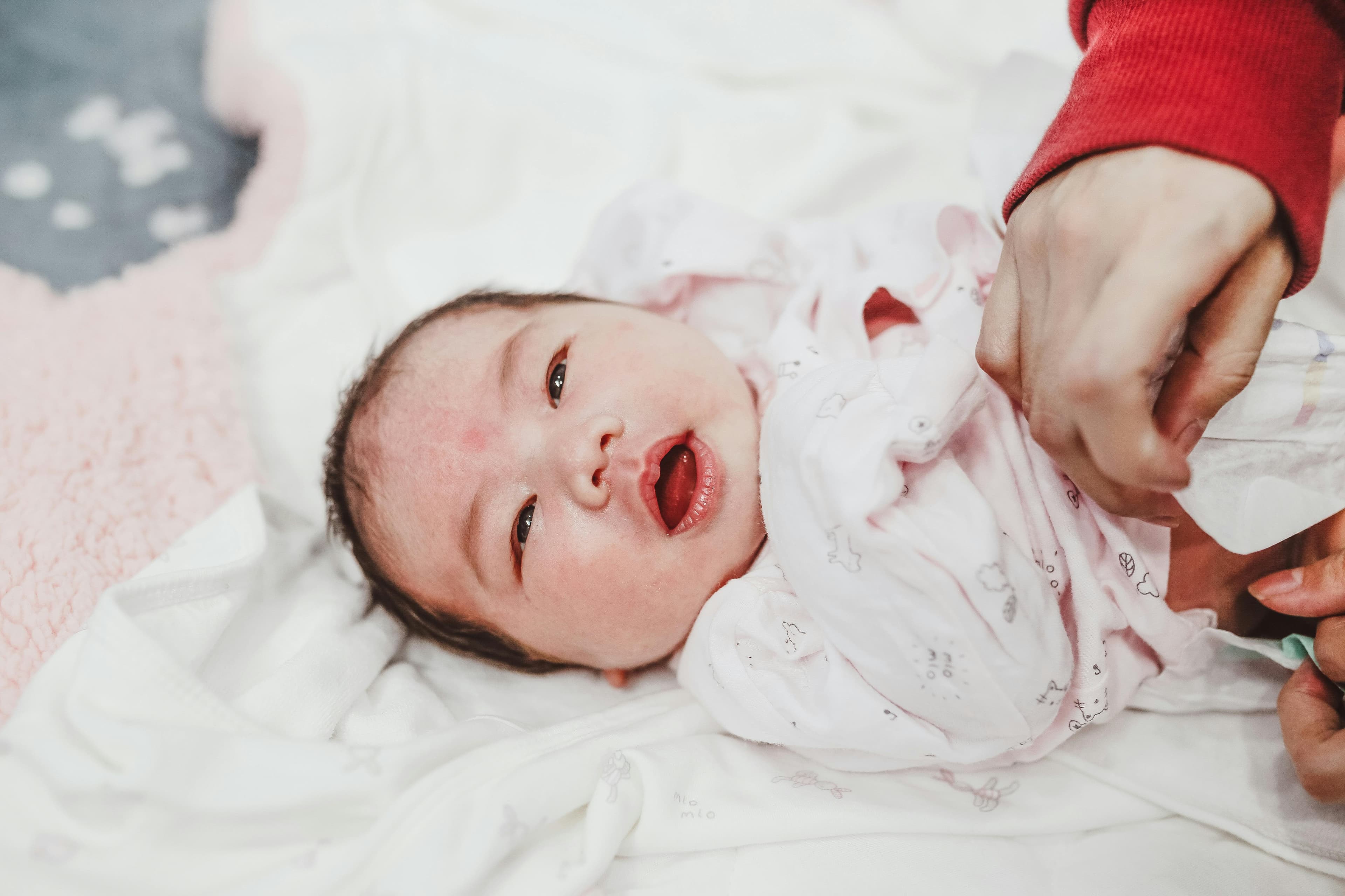 Parent gently cleaning baby's tongue with a soft cloth