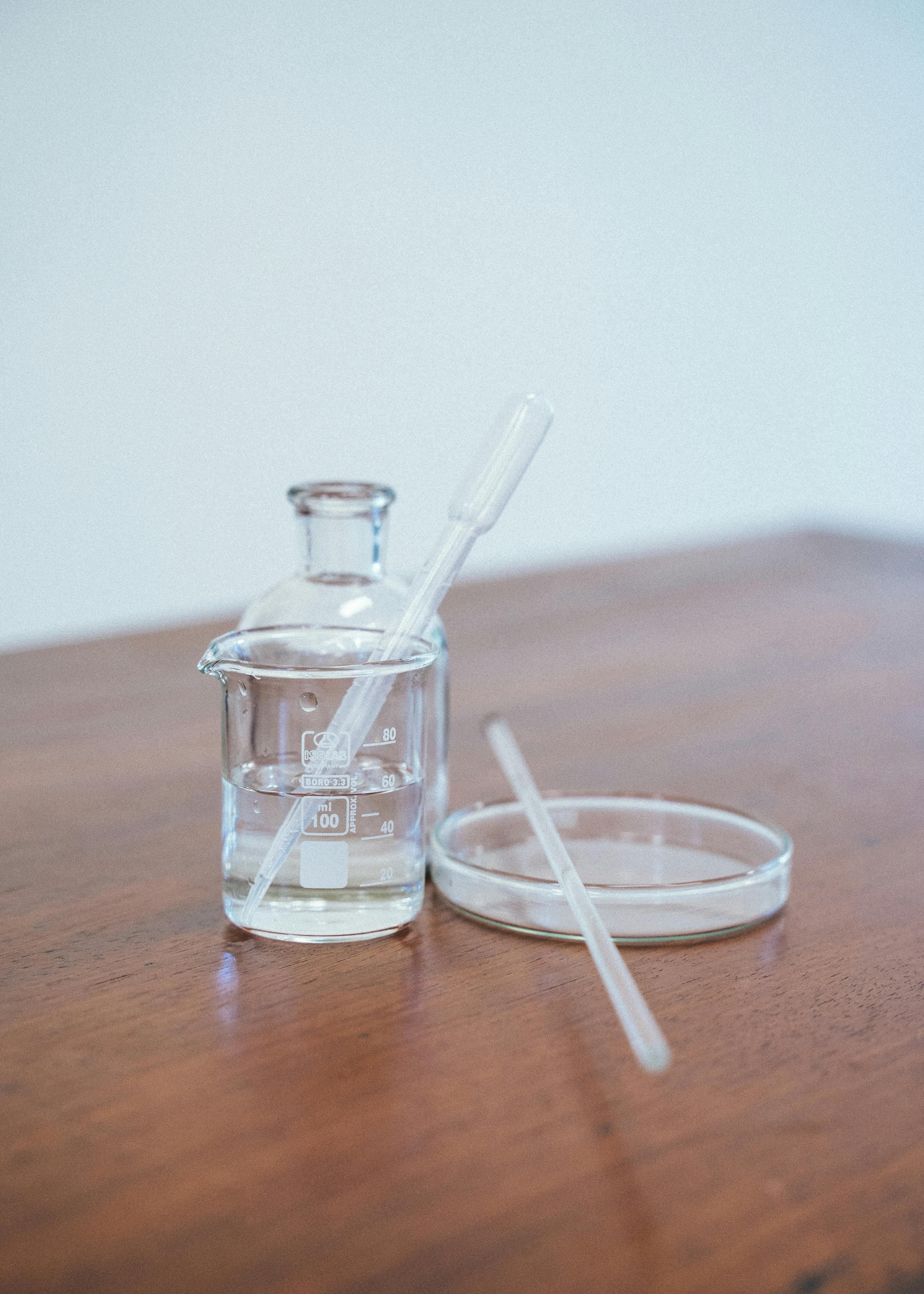 A glass of clear water with pH testing strips showing alkaline levels