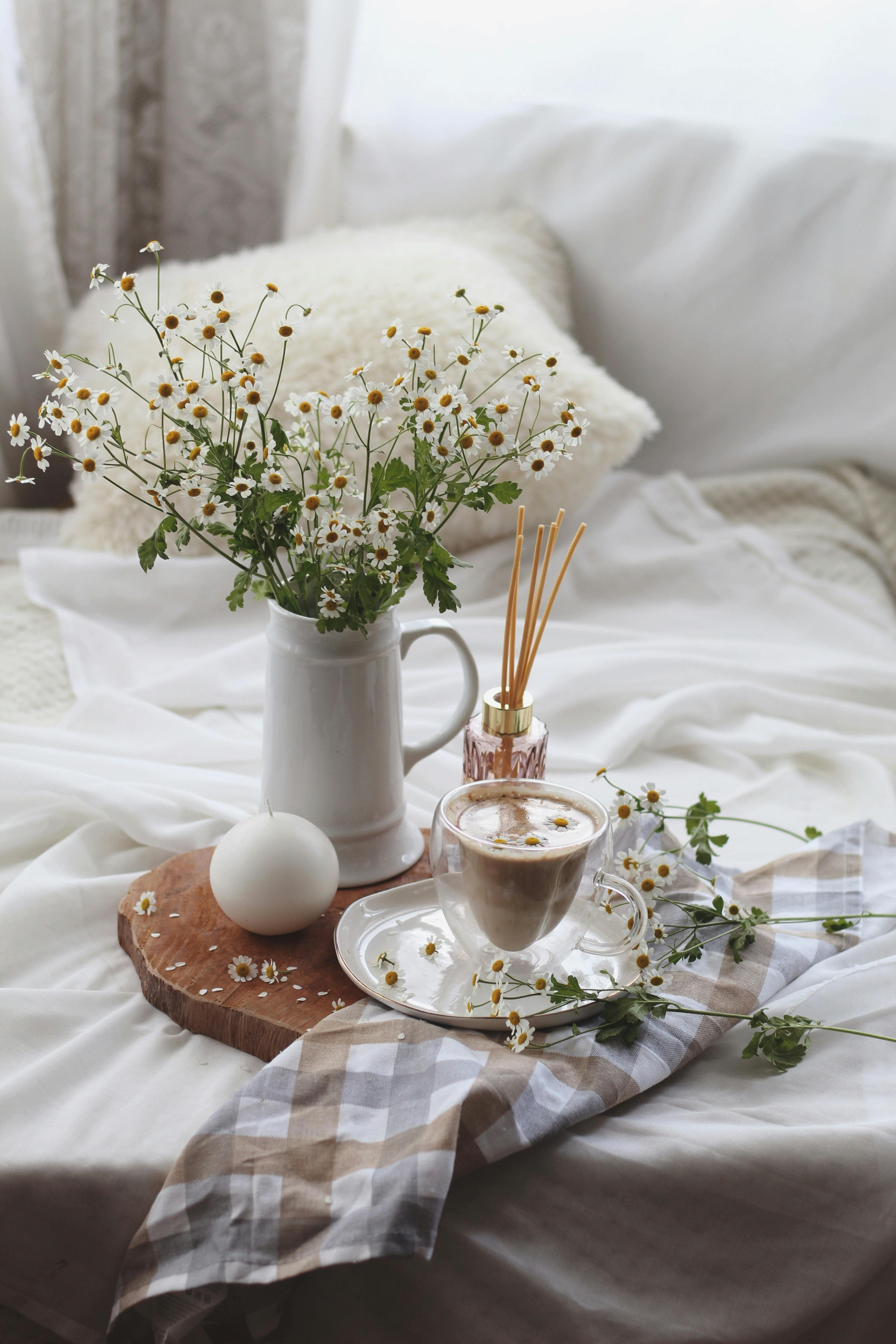 A steaming cup of chamomile tea with chamomile flowers scattered around