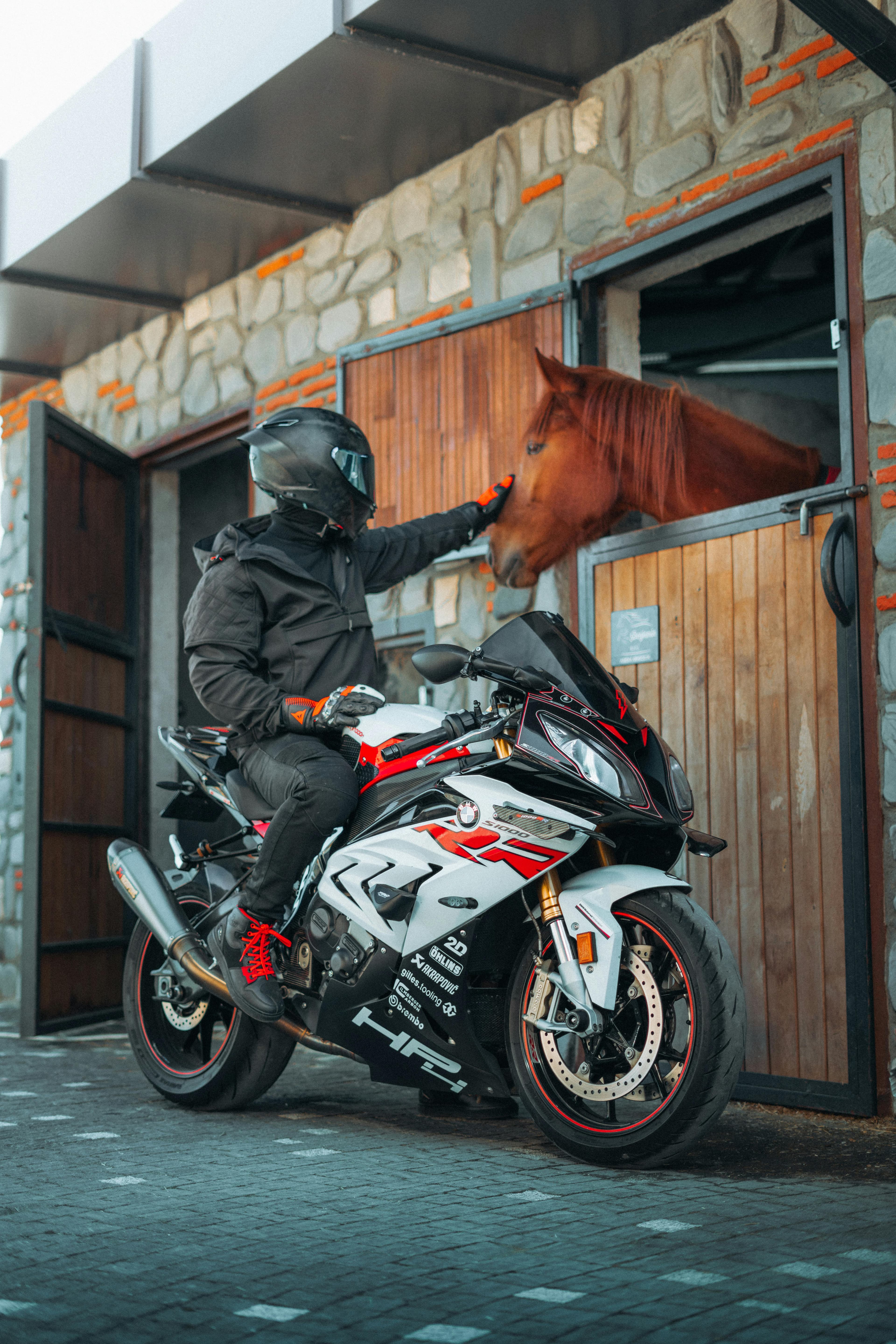 A motorcyclist wearing full safety gear including helmet, jacket, gloves, and boots