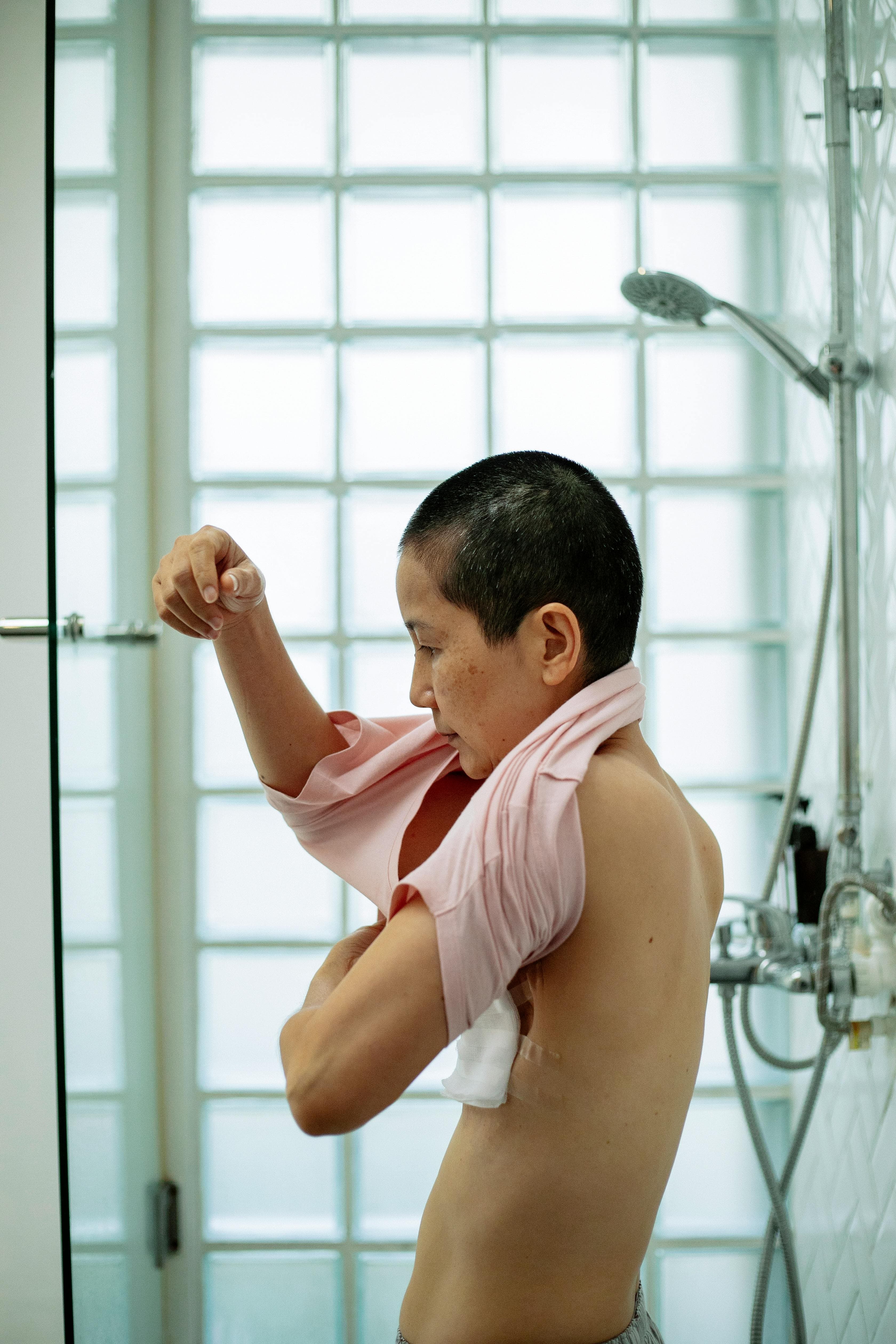 A woman performing a breast self-examination in front of a mirror